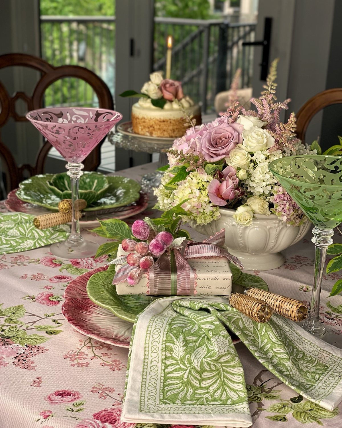 Floral dining table setting with pink tablecloth, green napkins, and fresh flower centerpiece.