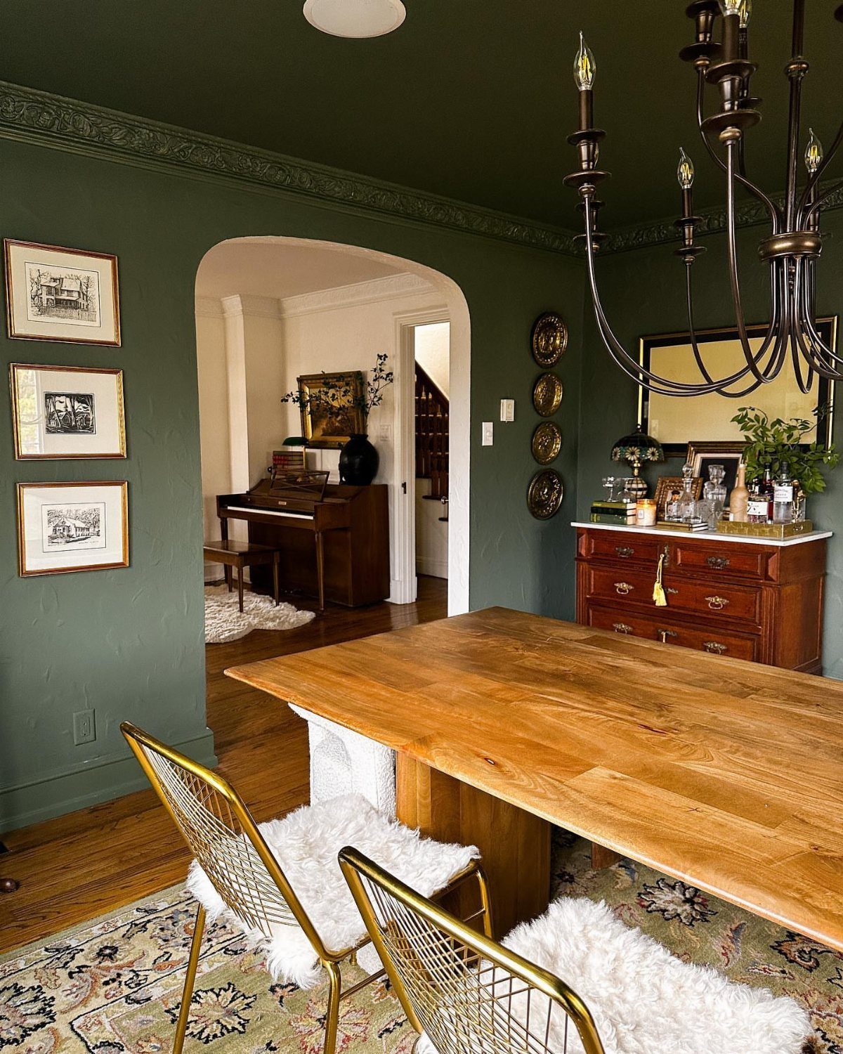 4 Evergreen Fog Dining Room Ideas with Photos 1 Deep sage green dining room walls with a wooden table and gold chairs.