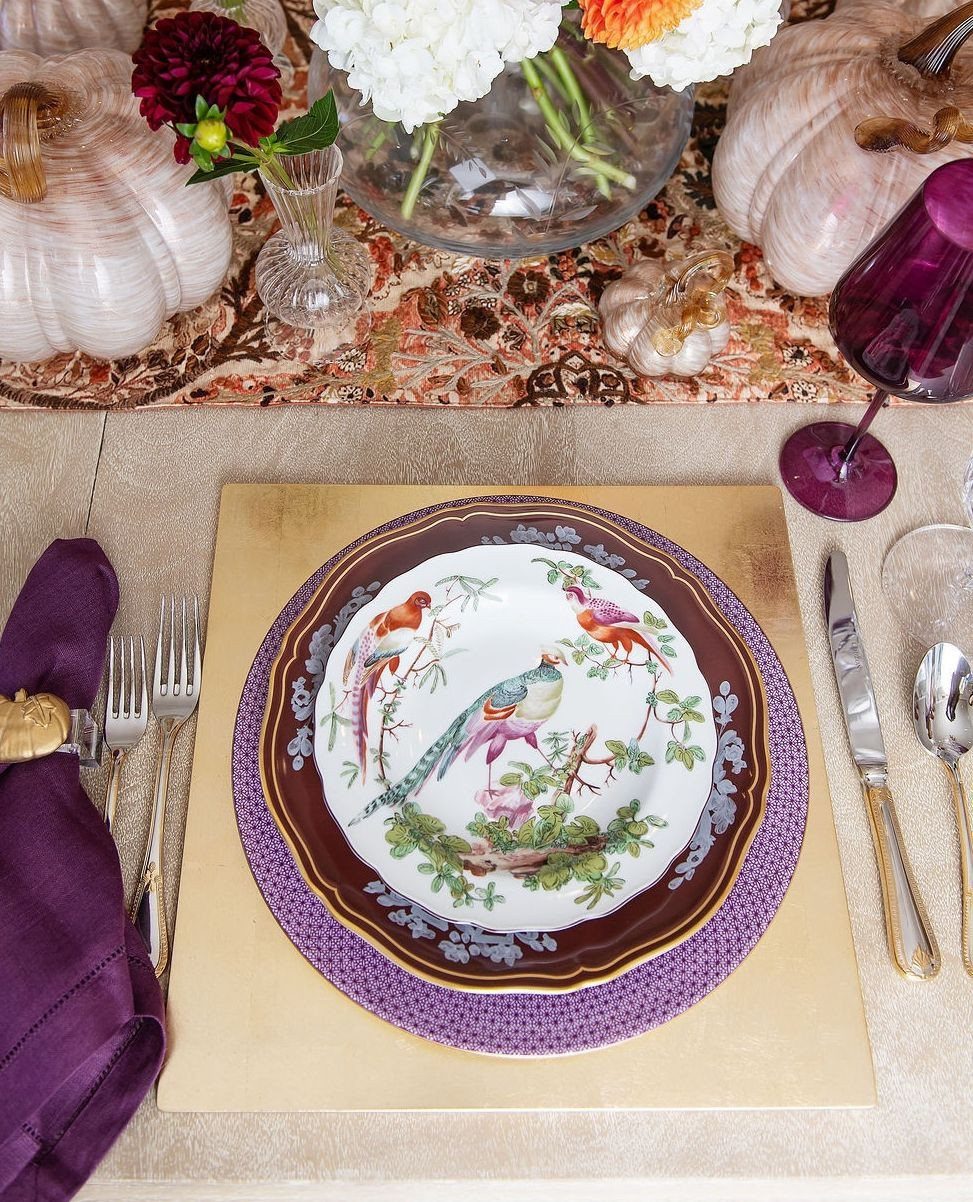 Autumn table setting with bird-patterned plate, purple accents, and white pumpkins.