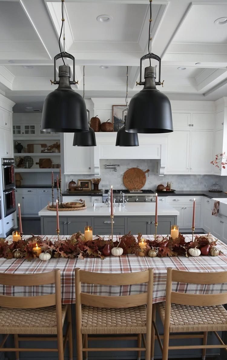 Plaid tablecloth on a dining table decorated with autumn leaves, pumpkins, and candles.
