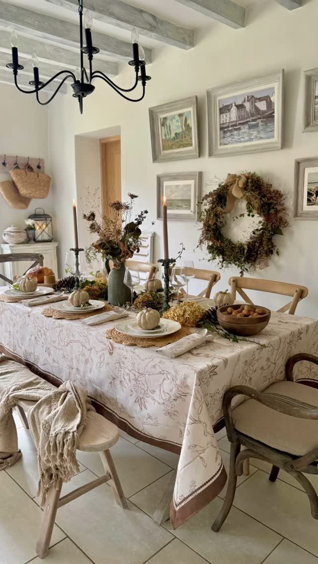 Dining table with a patterned tablecloth and a soft beige throw on a chair.