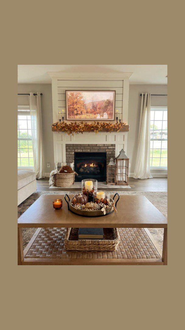 16 Fall Fireplace Mantel Decor Ideas with Photos 10 Autumn fireplace mantel with orange garland, landscape art, and pumpkins on a coffee table.