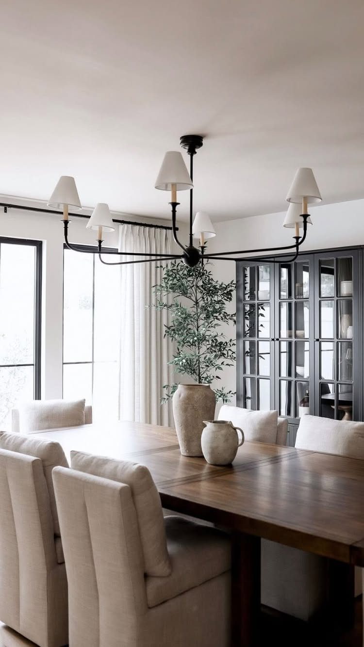 9 Farmhouse Style Dining Room Ideas with Photos 6 Large wooden dining table with beige upholstered chairs and a black multi-arm chandelier.