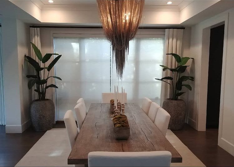 8 Feng Shui Dining Room Ideas for Balance and Flow 3 Wooden dining table with white chairs and large potted plants in a bright room