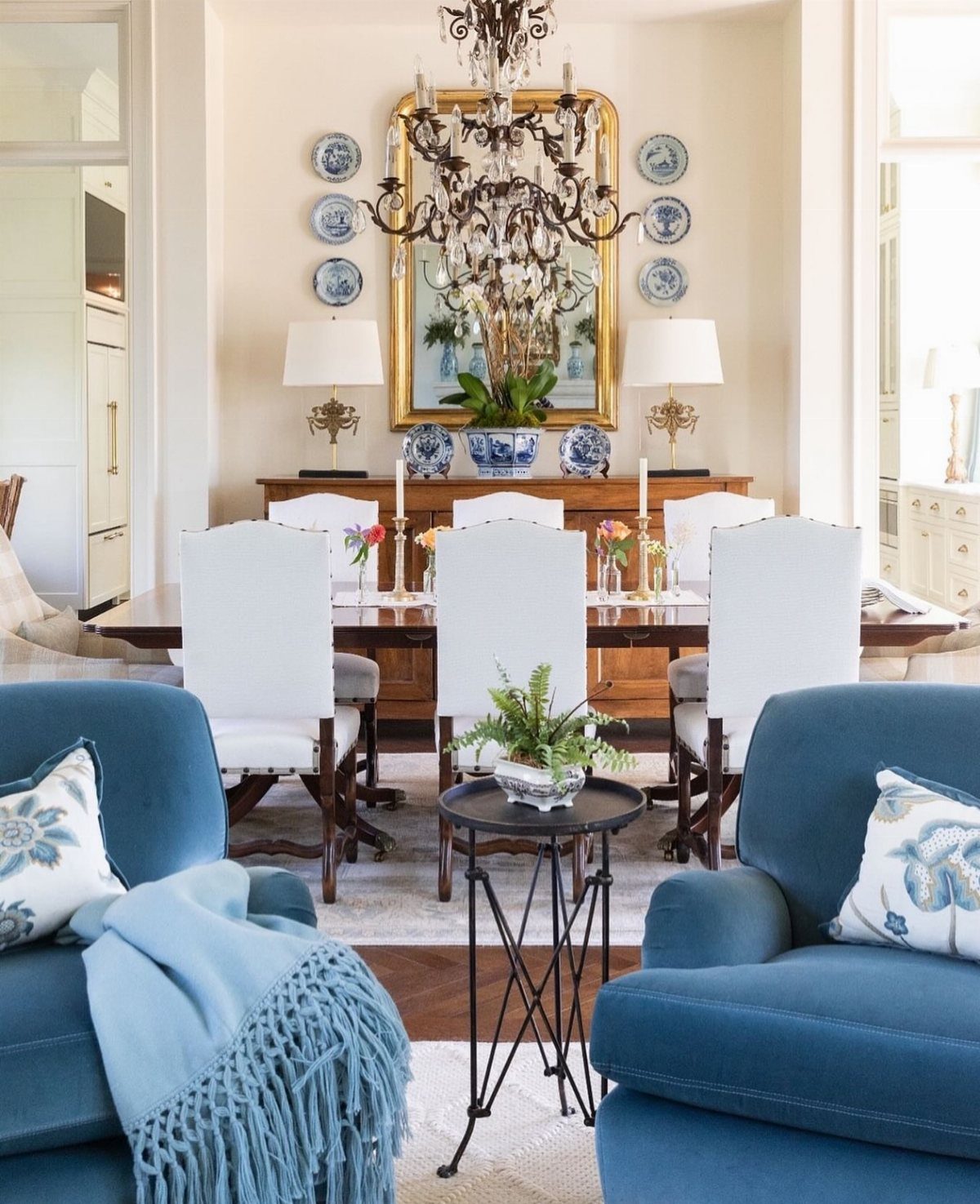13 Formal Dining Room Ideas for an Elegant Space 10 Symmetrical formal dining room with white chairs, ornate chandelier, and gold-framed mirror.
