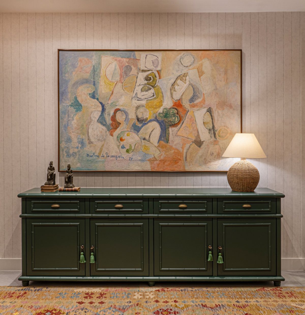 13 Formal Dining Room Ideas for an Elegant Space 2 Dark green sideboard with a large abstract painting and lamp against a paneled wall.