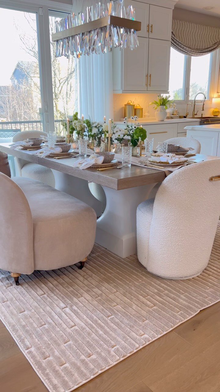 6 Formal Dining Table Decor Ideas for an Elegant Setting 3 Formal dining table with white flowers, candles, and cream chairs in a bright room.