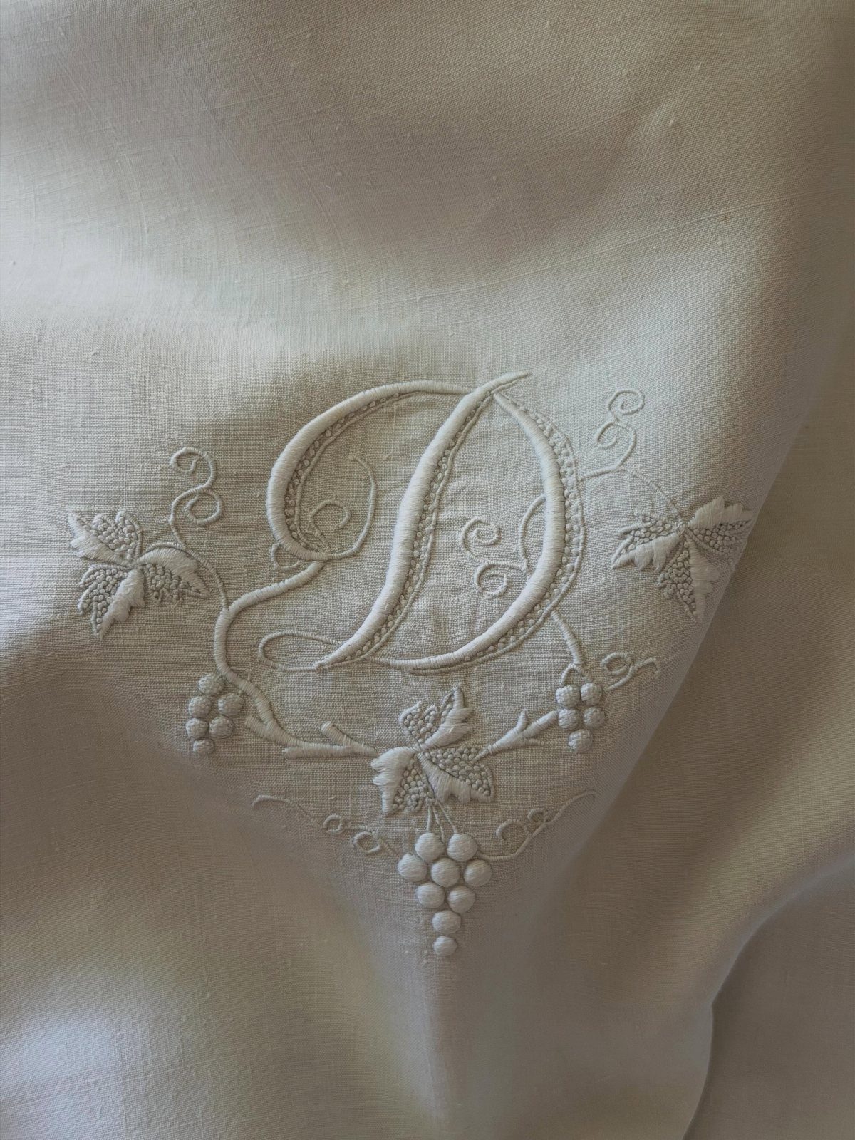 22 French Country Dining Room Ideas with Rustic Charm 11 White linen fabric with an embroidered letter D and grape vine patterns.
