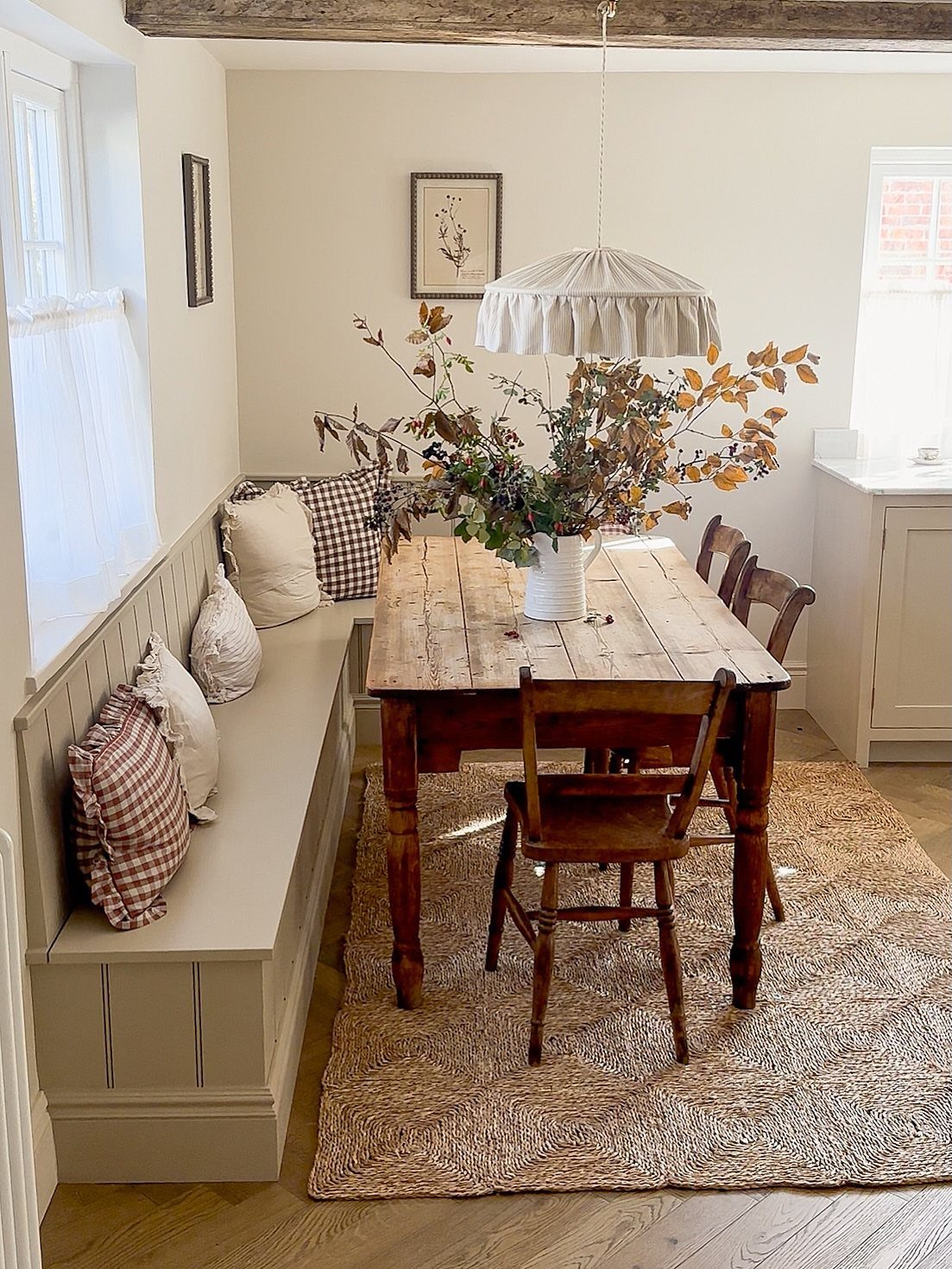 22 French Country Dining Room Ideas with Rustic Charm 10 Built-in dining bench with checkered pillows next to a rustic wooden farmhouse table.