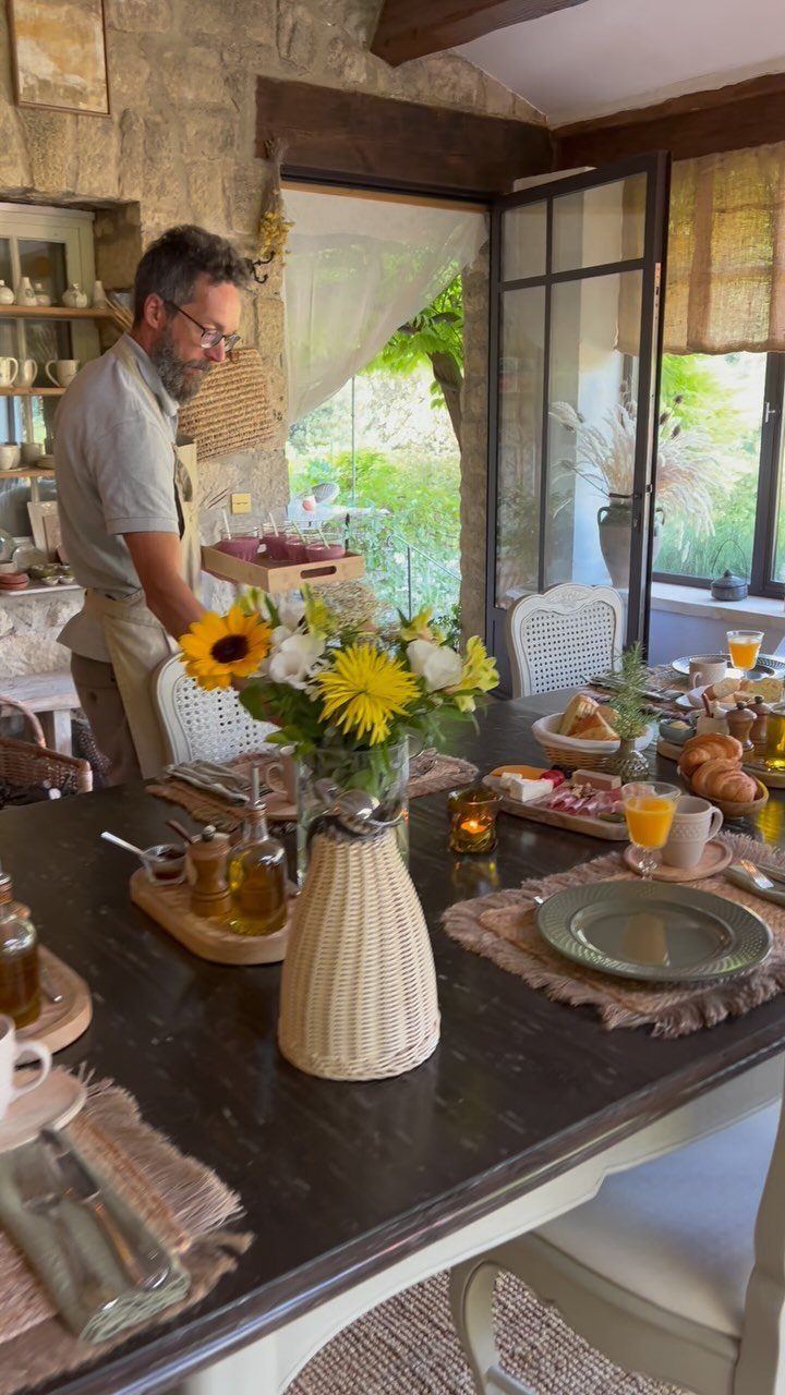22 French Country Dining Room Ideas with Rustic Charm 3 Dark wood farmhouse table set for breakfast in a rustic stone dining room.