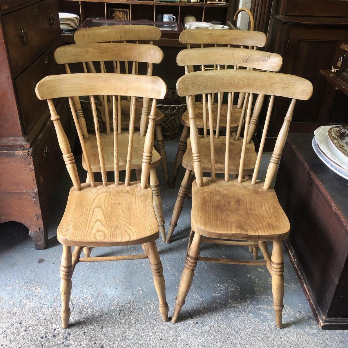 22 French Country Dining Room Ideas with Rustic Charm 5 Six light wooden spindle-back farm chairs arranged in a rustic indoor setting.
