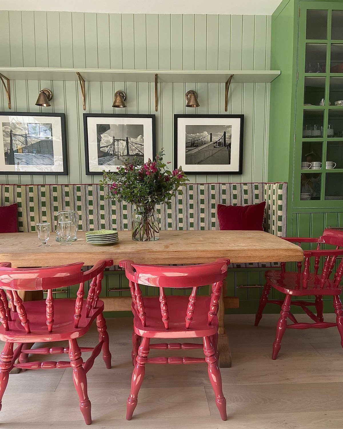 11 Green Painted Dining Room Ideas with Photos 11 Green paneled dining room with a wooden table and vibrant pink chairs.