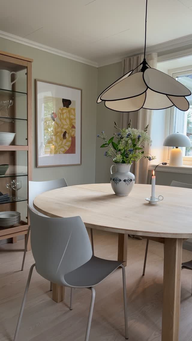 11 Green Painted Dining Room Ideas with Photos 10 Pale green dining room with light wood table, grey chairs, and petal pendant lamp