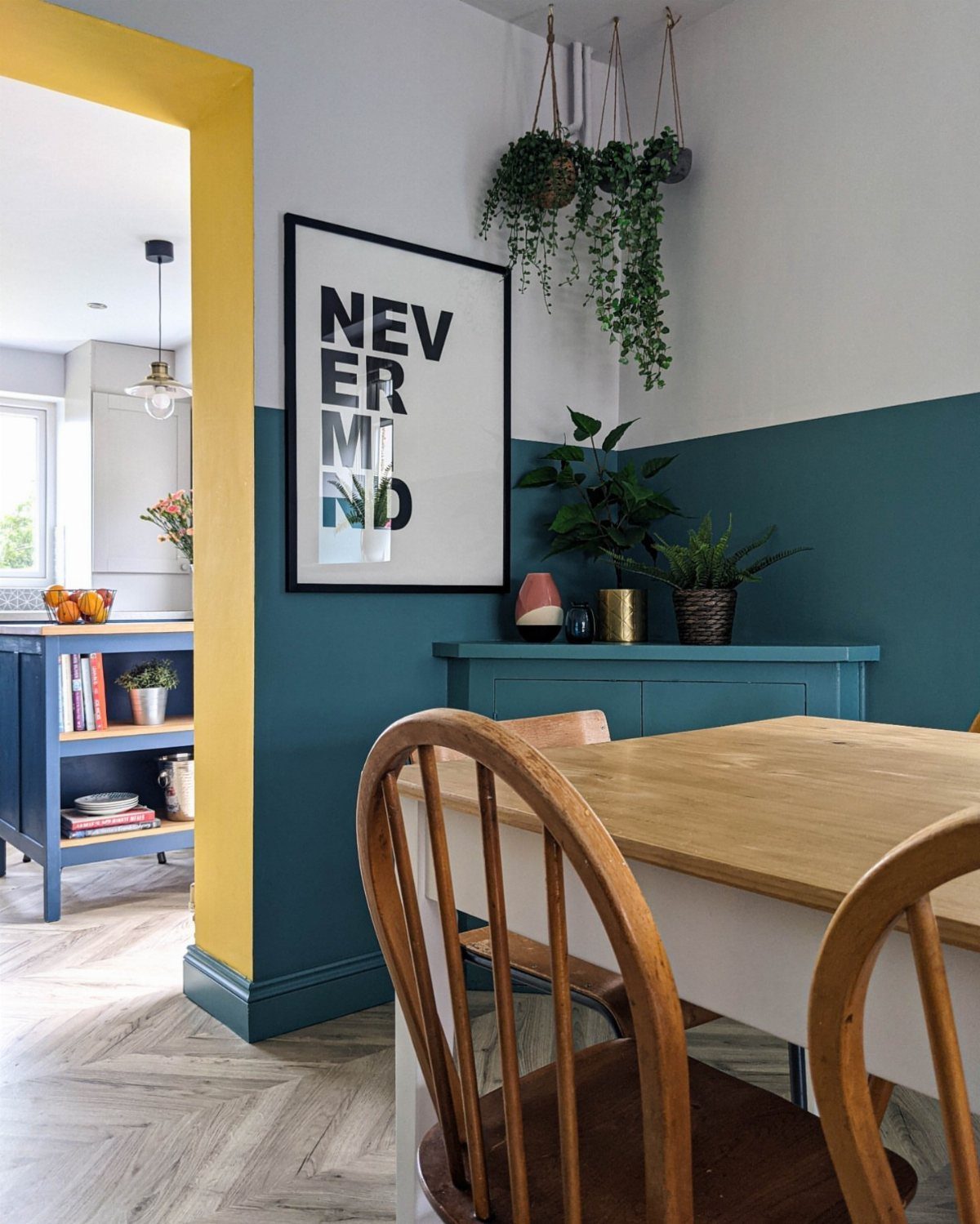 11 Green Painted Dining Room Ideas with Photos 6 Dining room with half-painted dark teal walls, wooden furniture, and hanging indoor plants.