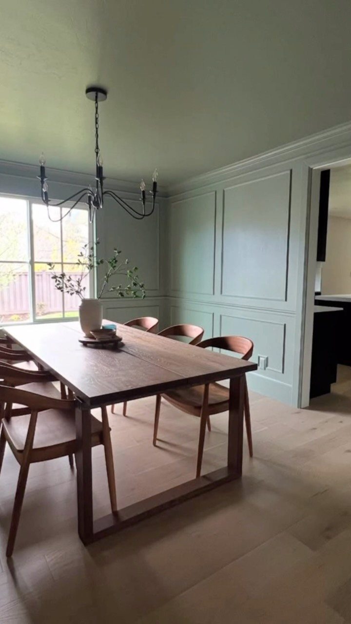 9 Green Walls for Dining Room Ideas with Photos 3 Sage green dining room walls with wainscoting, wooden table, and black chandelier.