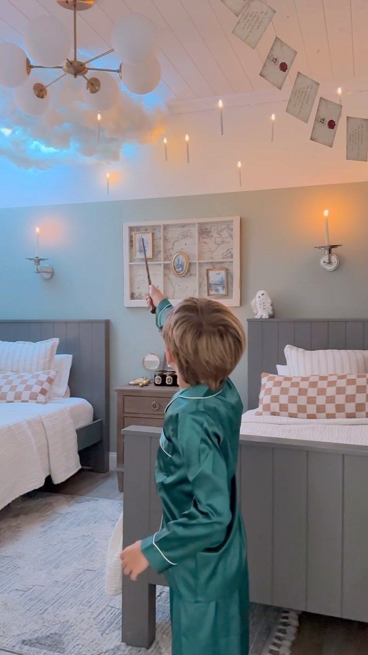 16 Halloween Room Decor Ideas to Set the Scene 10 Child in pajamas in a bedroom with floating white candles and balloons.