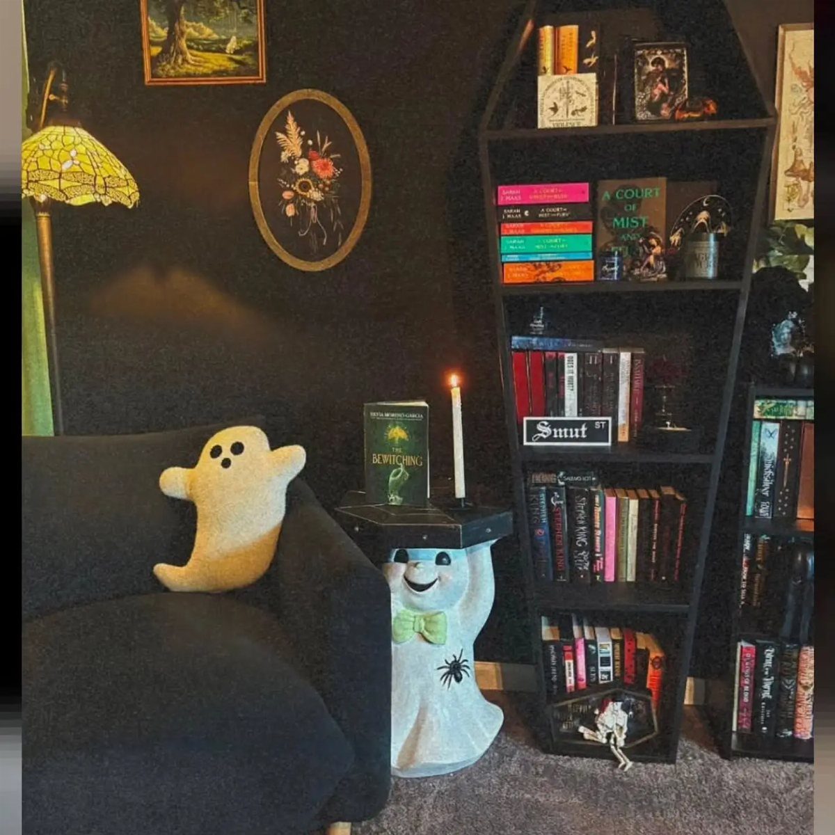 16 Halloween Room Decor Ideas to Set the Scene 3 Dark room with a black bookshelf, ghost pillow, and spooky gothic library decorations.
