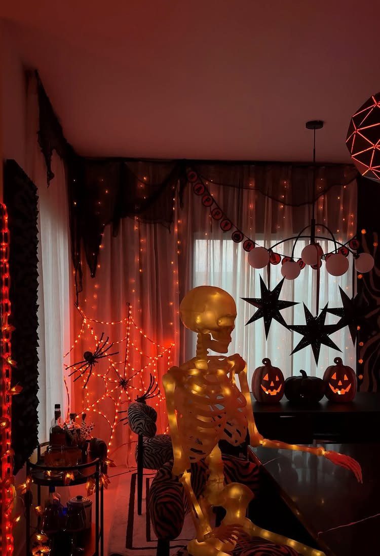 16 Halloween Room Decor Ideas to Set the Scene 11 Glowing orange skeleton and carved pumpkins in a room with spooky Halloween decorations.