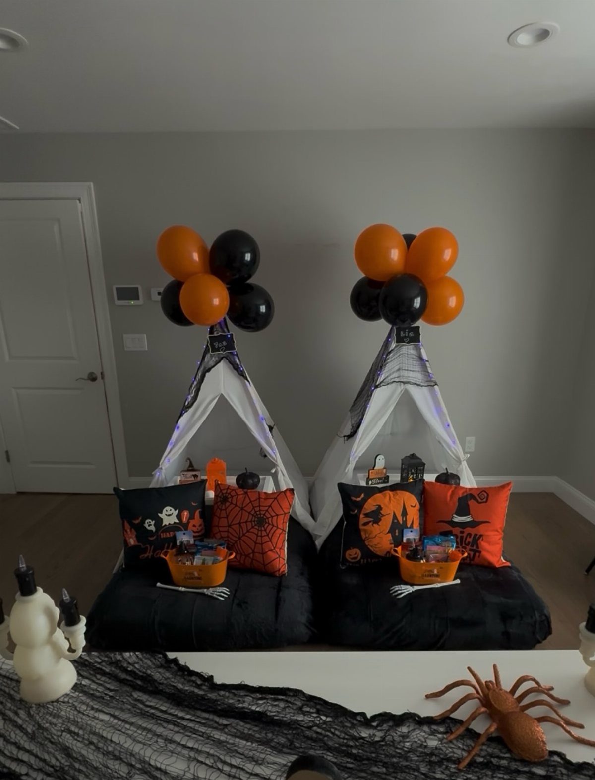 16 Halloween Room Decor Ideas to Set the Scene 12 Two Halloween teepees with orange and black balloons, spooky pillows, and treat buckets.