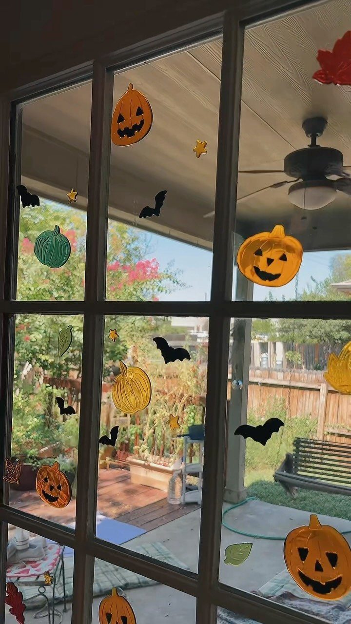 16 Halloween Room Decor Ideas to Set the Scene 8 Halloween pumpkin and bat stickers on a white window pane overlooking a sunny patio.