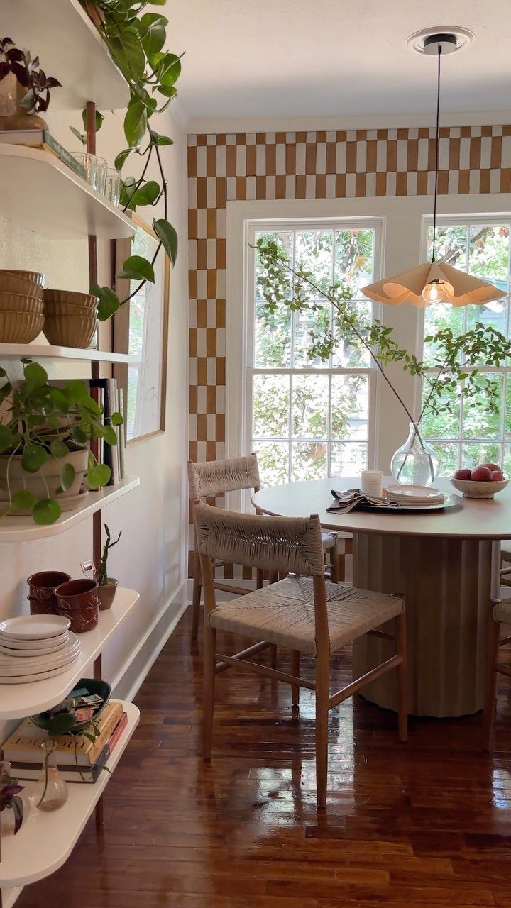 Dining room with a brown and white checkered accent wall and round table.