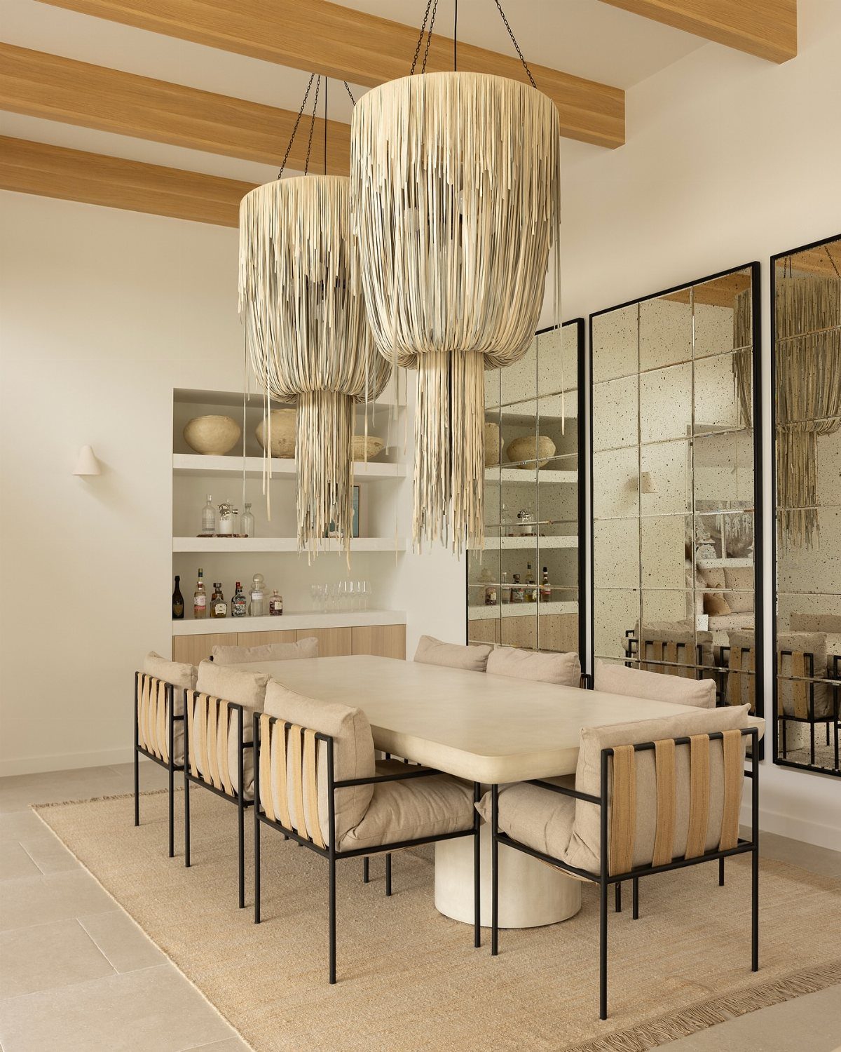 Modern dining room featuring large black-framed mirrors on the wall and woven pendant lights.