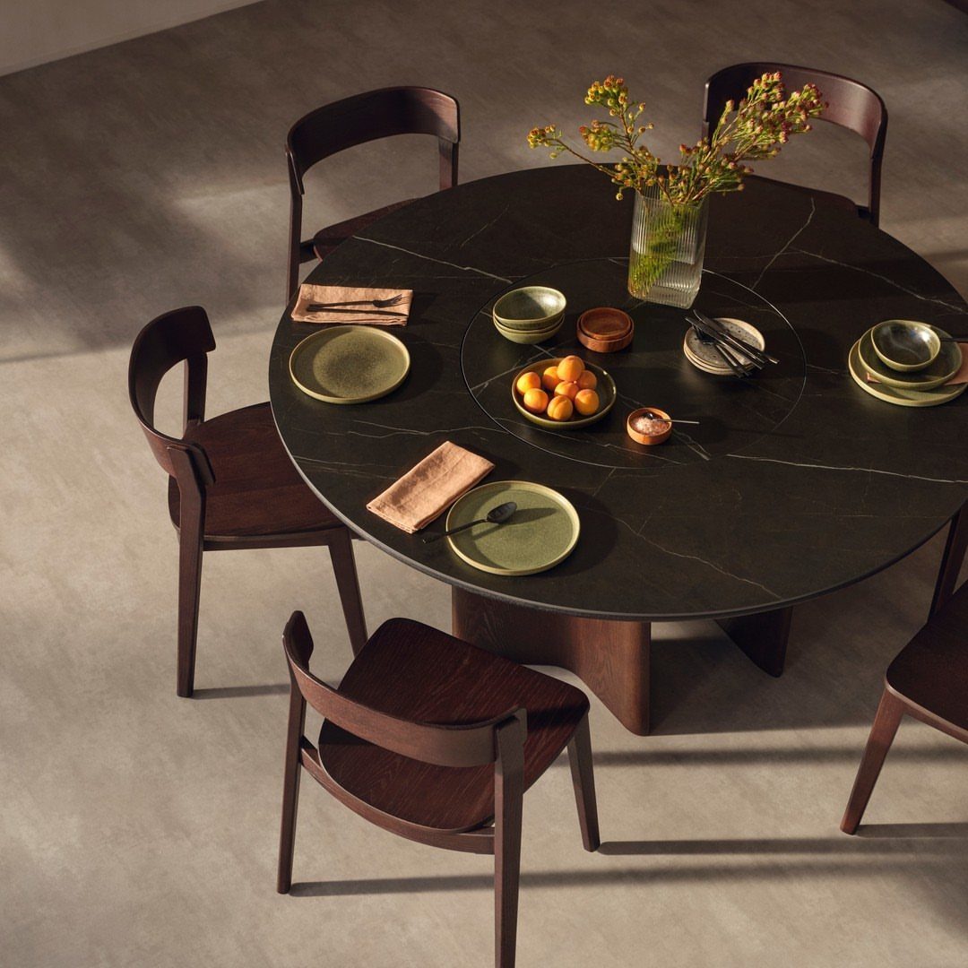 Round black marble dining table with a lazy susan and dark wood chairs.