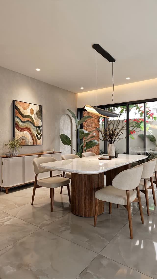 Modern dining room with marble table, cream chairs, and abstract wall art.