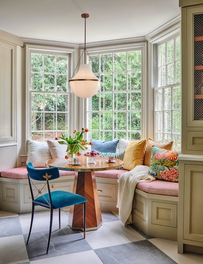 11 Living Dining Room Combo Ideas for Small Spaces 6 Built-in L-shaped dining bench with pink cushions and a round wooden table.