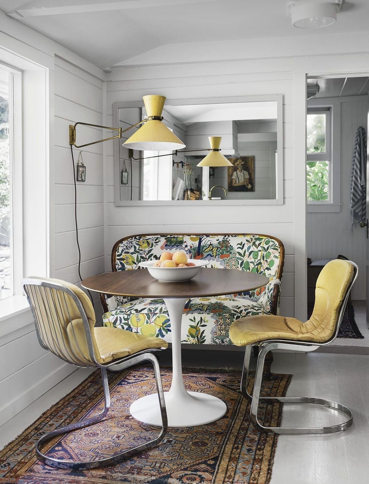 12 Living Dining Room Decor Ideas for Combined Spaces 3 Round wooden dining table with mismatched yellow chairs and a floral settee on a rug.