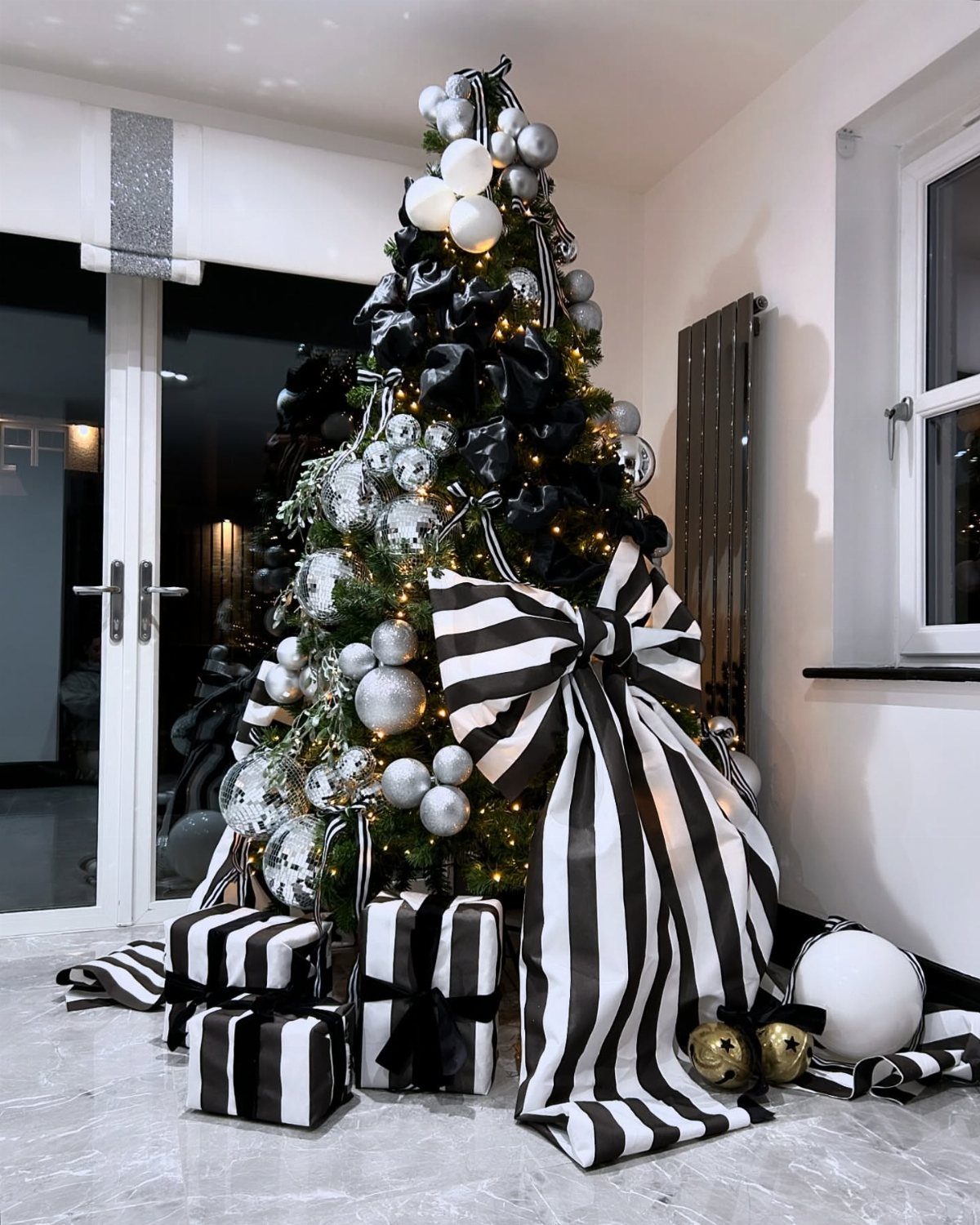 14 Modern Christmas Living Room Ideas with Photos 2 Christmas tree decorated in black and white with striped ribbons and gift boxes.
