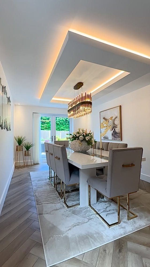 Modern dining room with recessed ceiling LED lighting and a gold chandelier.
