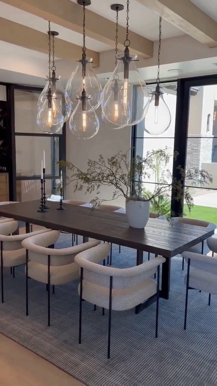 Glass teardrop pendant lights hanging over a modern dark wood dining table