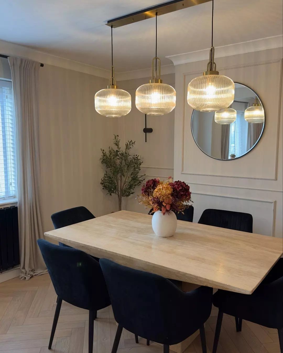 Three ribbed glass globe pendant lights hanging over a wooden dining table.