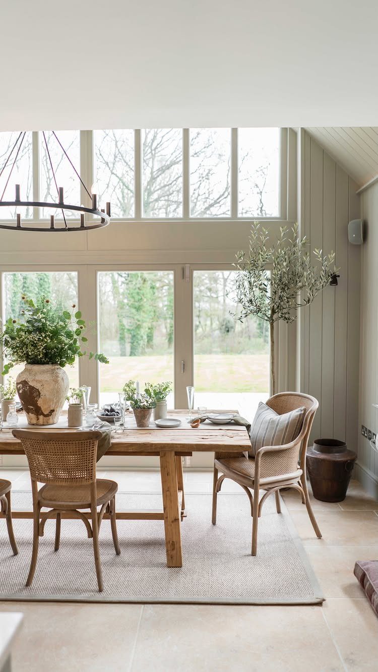 Rustic wooden dining table with woven chairs and a black circular chandelier.