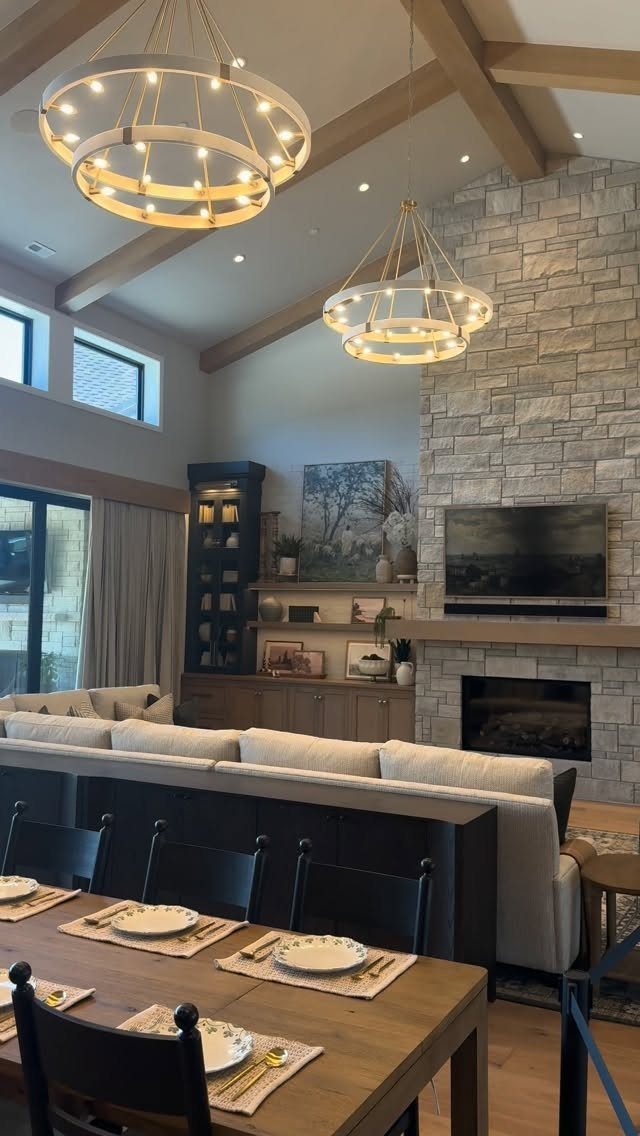 14 Modern Farmhouse Dining Room Ideas with Style 4 Two tiered circular gold chandeliers hanging from exposed wooden beams in a dining room.