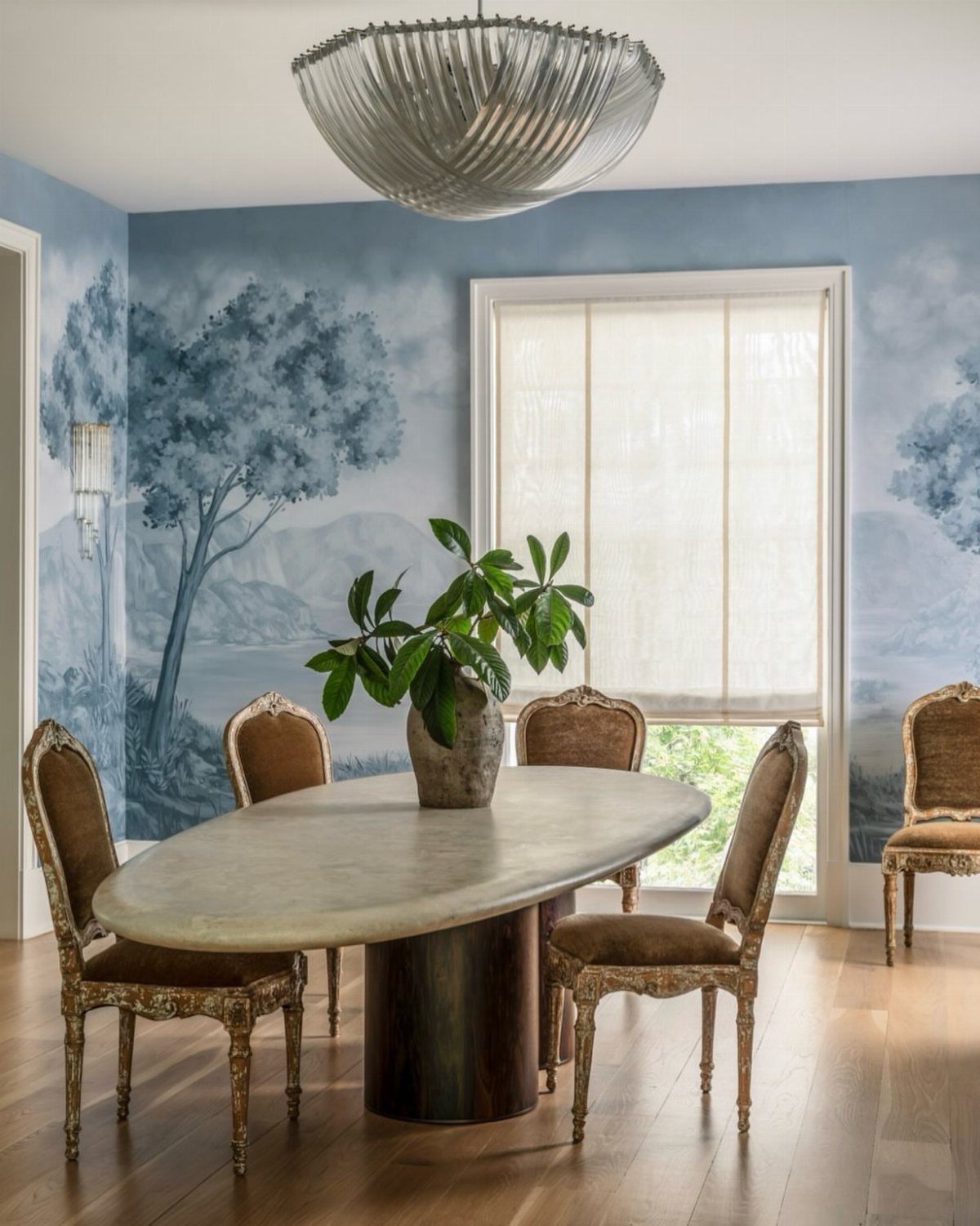 23 Modern Luxury Dining Room Ideas with Photos 23 Oval stone dining table with ornate gold chairs in a room with blue murals.