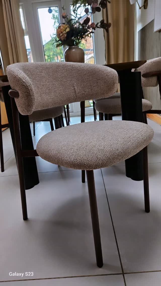 Minimalist dining chair with beige fabric upholstery and dark brown wooden legs.