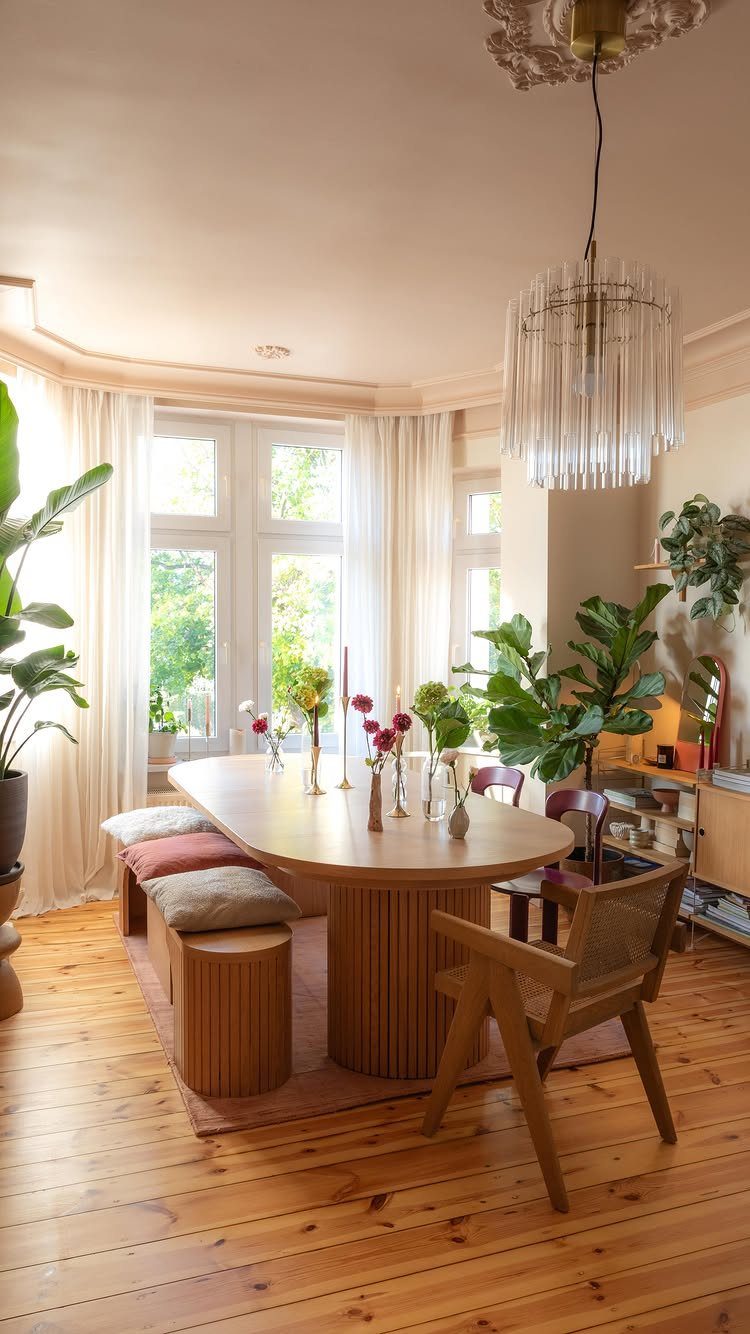 Oval light wood dining table with matching bench and chair in bright room