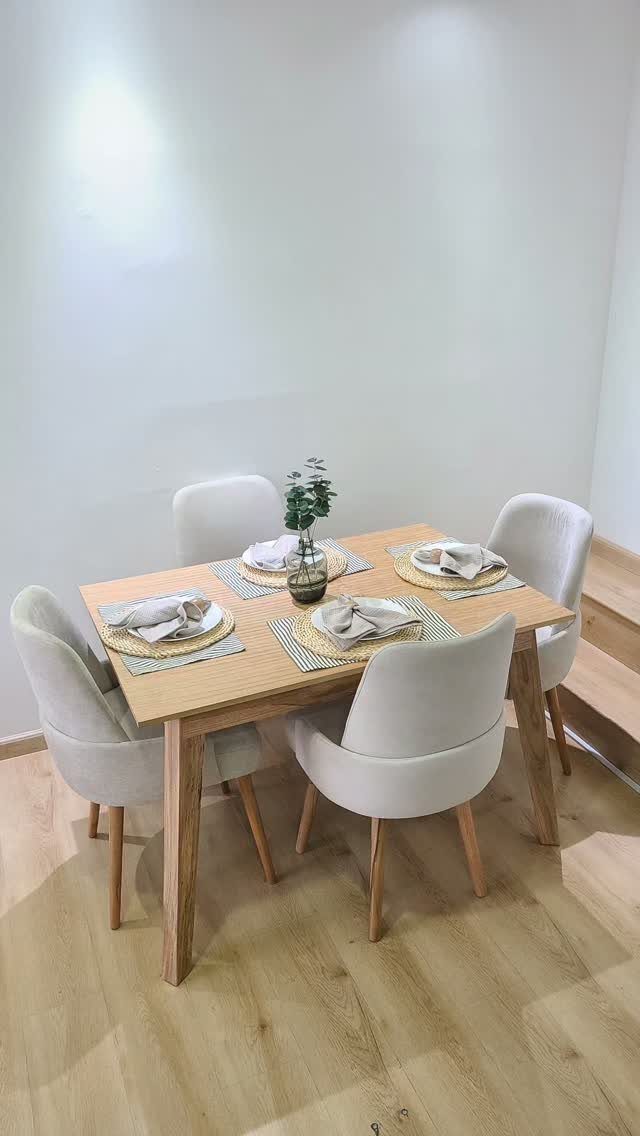 Rectangular light wood dining table with four white chairs and minimalist table settings.