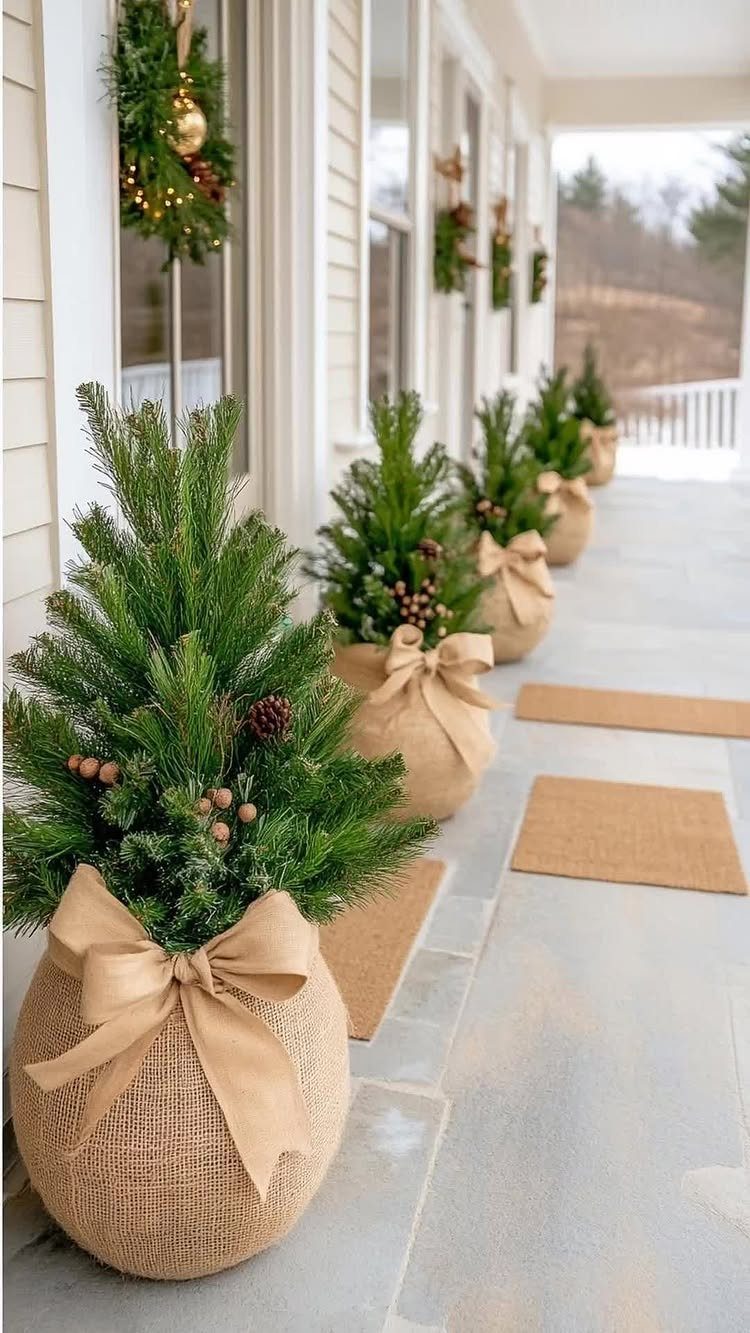 10 Neutral Color Christmas Decor Ideas for a Cozy Home 2 Small evergreen trees in burlap pots with beige bows on a white porch.