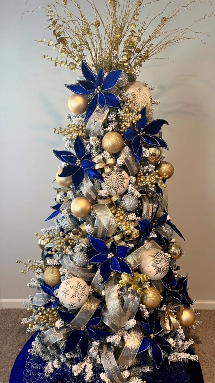 29 New Ideas for Christmas Decorating to Try in 2026 26 Christmas tree decorated with blue velvet flowers, gold ornaments, and silver ribbons.
