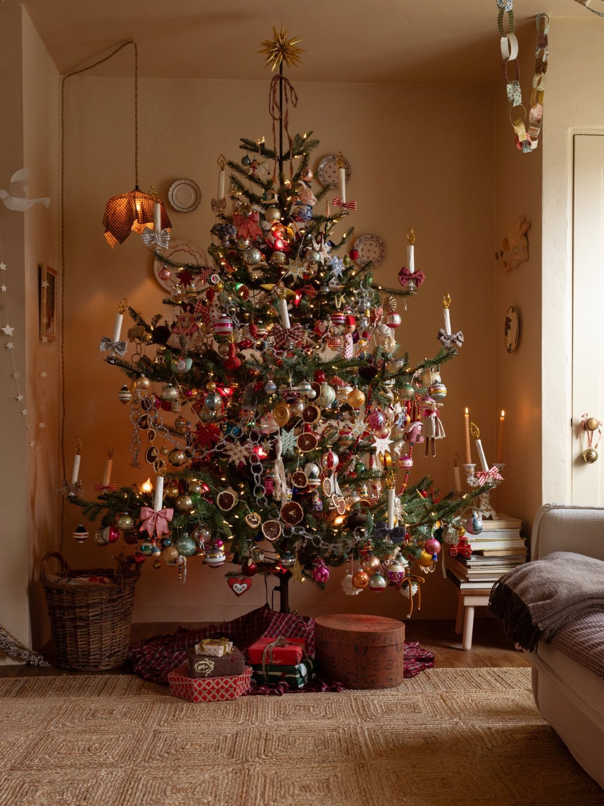 29 New Ideas for Christmas Decorating to Try in 2026 6 Decorated Christmas tree with colorful ornaments and candles in a cozy living room.
