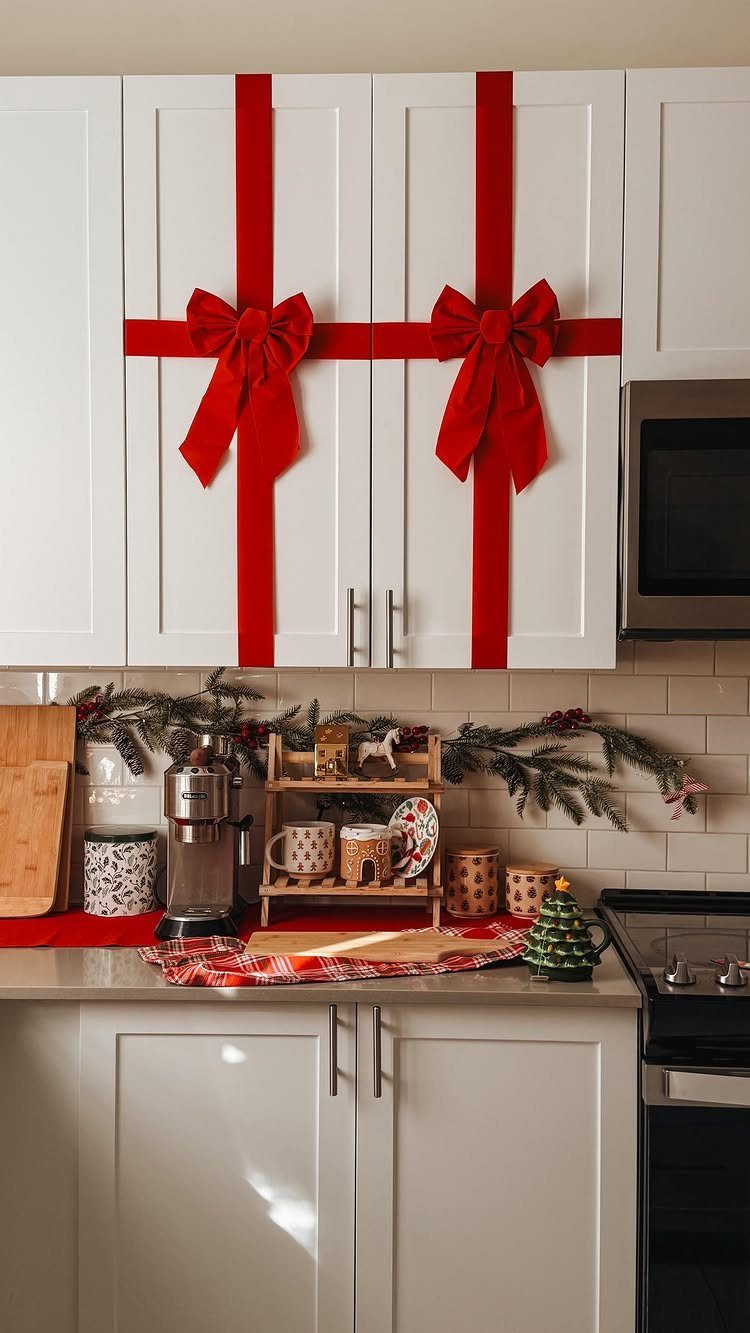 29 New Ideas for Christmas Decorating to Try in 2026 20 White kitchen cabinets wrapped with red ribbons and bows like Christmas presents.