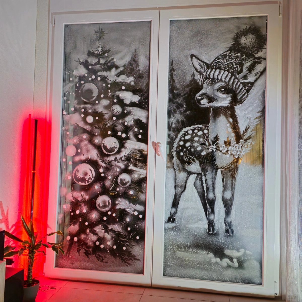 29 New Ideas for Christmas Decorating to Try in 2026 9 Frosted glass window panes featuring a snowy Christmas tree and a winter deer.