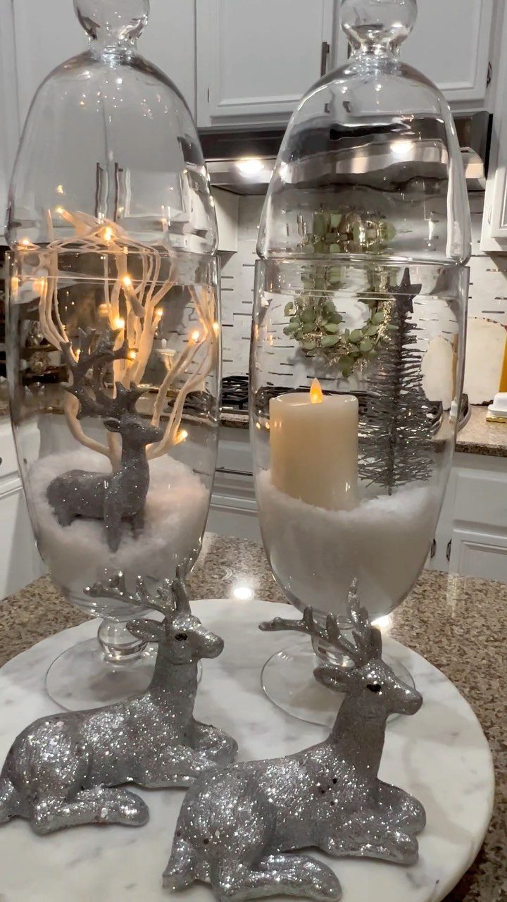 29 New Ideas for Christmas Decorating to Try in 2026 4 Glass cloches with a miniature wreath, candle, and silver deer on marble.
