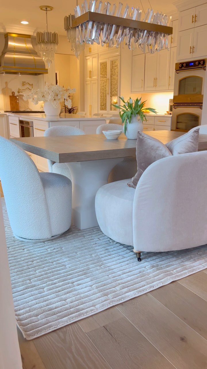 White textured area rug under a modern dining table with curved white chairs.