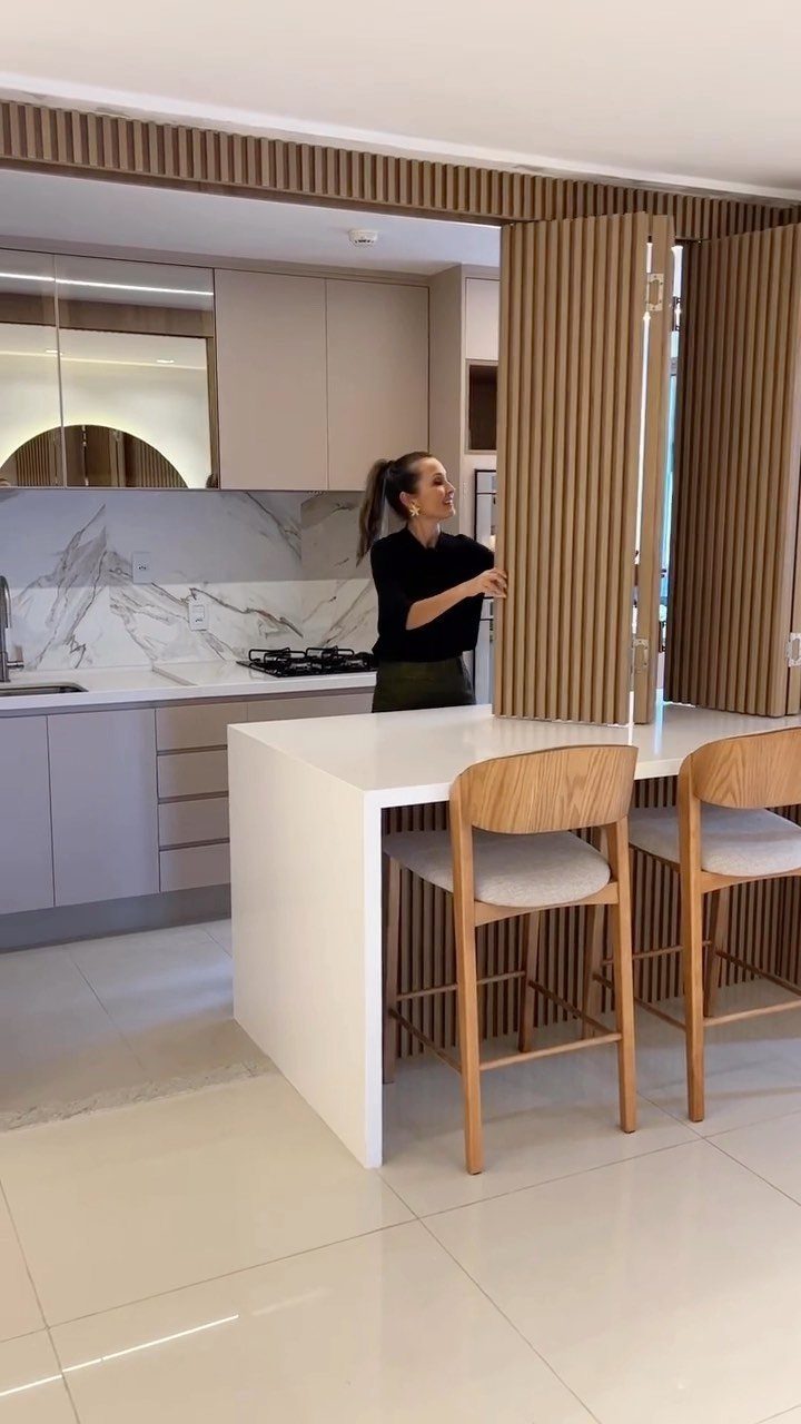Modern kitchen island with wooden bar stools and a vertical slat room divider.