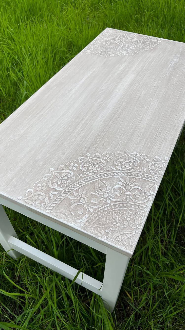 5 Painted Dining Room Table Ideas with Photos 4 White painted wooden table with decorative stenciled patterns sitting on green grass.