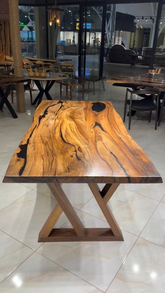 11 Rustic Modern Dining Room Ideas with Real Character 3 Live edge wooden dining table with dark resin fills and geometric X-shaped base.